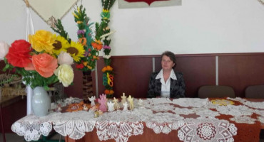 Siedząca Pani Lucyna Jędrzejczyk przy palmach i kwiatach oraz serwetkach na stole
