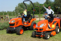 Zdjęcie przedstawia dwie pomarańczowe kosiarki (traktory) do trawy
