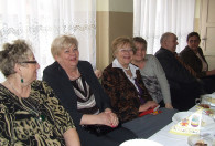 grupa kobiet oraz mężczyzna przy stole podczas obchodów dnia kobiet