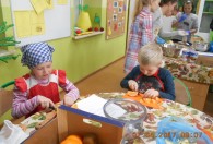 Zdjęcie przedstawia dzieci podczas krojenia pomarańczy