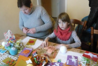 Zdjęcie przedstawia kobietę z dzieckiem podczas zdobienia kartek świątecznych