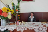 Siedząca Pani Lucyna Jędrzejczyk przy palmach i kwiatach oraz serwetkach na stole