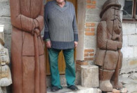 Zdjęcie przedstawia Pana Henryka Staszko przed wejściem do domu, obok rzeźby